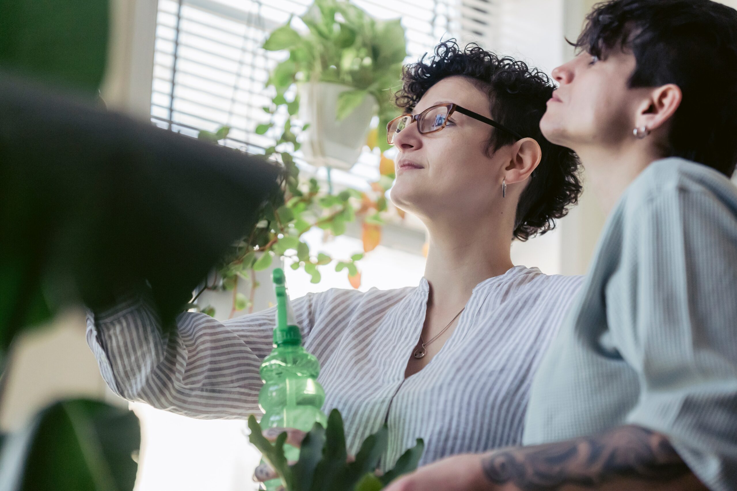 twee mensen die kijken naar hun plant met een plantenspuit in de hand